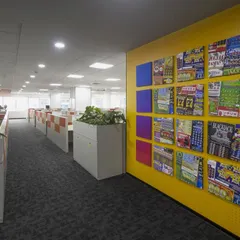 A bright yellow accent wall at the Scientific Games office features a curated gallery of the company's products. This serves as both a vibrant design element and a constant reminder of the team's creative output and success.