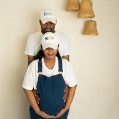 A sweet and casual standing pose for a couple. The focus is on the gentle embrace and the shared excitement for their new arrival.