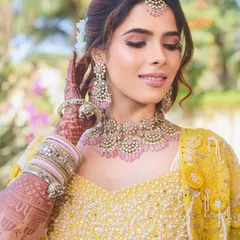 A close-up on the bride's radiant Haldi makeup. The soft pink eyeshadow and glowing skin create a look that is both elegant and joyful.