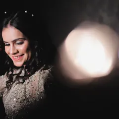 An artistic bridal portrait using lens flare and bokeh for a dreamy effect. The focus is on her happy, candid expression as she gets ready for her big day.