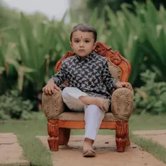 Beyond the candid shots, I also craft classic portraits. This little gentleman, dressed in a traditional kurta, looks so poised on this miniature throne. It shows a different kind of *nazakat* or grace that I love to find in every child.