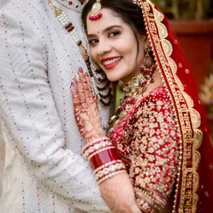 A bride's happy smile as she rests her head on her groom's chest. This close-up shot focuses on her expression of comfort and joy, showcasing her intricate henna and bridal jewelry.
