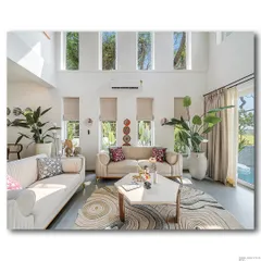 Natural light floods this double-height living room at Casa D Umravi, creating a bright and airy atmosphere. The high windows draw the eye upward, emphasizing the spaciousness, while the clean lines of the furniture and the organic patterns of the rug create a sense of modern, relaxed luxury.