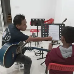 A guitar teacher guiding his student through a new piece of sheet music. We focus on building strong fundamentals.