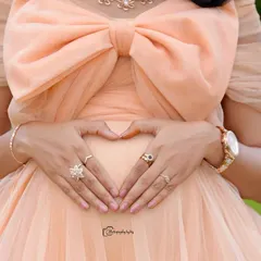 A close-up shot of hands forming a heart shape on the baby bump, a simple and beautiful way to show love.