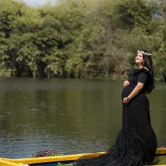Our black off-the-shoulder mermaid gown is a client favorite. It offers a timeless, elegant look that beautifully accentuates the baby bump, perfect for both studio and outdoor settings.