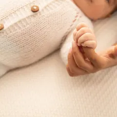 A tiny hand holding tight to a parent's finger. This close-up shot shows the delicate details of their little fingers and the strength of their grip.