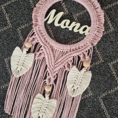 A close-up of our custom macrame nameplate for 'Mona'. The combination of dusty rose macrame, natural wooden beads, and delicate leaf details makes for a beautiful and personal piece.