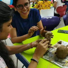 The joy of collaboration! Two participants work together on a Ganesha sculpture during a corporate workshop, sharing smiles and creative energy.