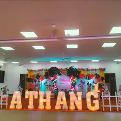A grand Mickey Mouse themed first birthday celebration in a hall, with large marquee letters, a full character backdrop, and classic red, black, and yellow balloon decor.