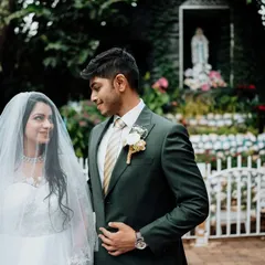 A moment of quiet reverence at a Catholic wedding. The bride and groom stand before a grotto of the Virgin Mary, a beautiful symbol of faith and blessing on their union.