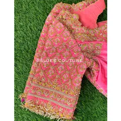 A close-up of the sleeve of a pink velvet bridal blouse. You can see the dense, intricate zardozi and pearl work, finished with delicate tassels for added movement and charm.
