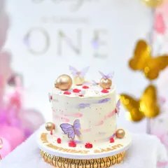 A delicate butterfly-themed cake with pastel colors and gold accents, perfect for a first birthday.