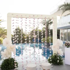 The poolside seating area, featuring a backdrop of hanging handmade organza flowers in shades of lilac and white.