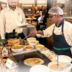 A chef prepares fresh, soft dosas at a live South Indian counter. This station is always a crowd-pleaser, offering a taste of authentic flavours made to order for each guest.