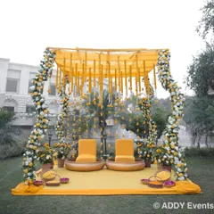 A beautiful poolside Haldi mandap. The structure is draped in yellow fabric and adorned with garlands of white and yellow flowers, creating a fresh and festive atmosphere.