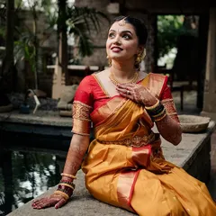 A bride sits by a small indoor pond, her expression full of wonder, as she takes in the beauty of her surroundings.