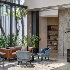 This view connects the sleek reception desk with the comfortable client waiting area. The use of natural materials like wood and stone, along with ample greenery, creates a welcoming and high-end experience from the moment one enters.
