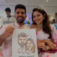 A happy couple at their wedding celebration with their caricature, featuring their custom hashtag #NishDilHaaRhea. It's a wonderful keepsake from their special day.