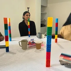 Collaboration is key in my workshops. Here, educators work together at a table, using LEGO blocks to build towers, an activity designed to teach concepts of balance, patterns, and teamwork.