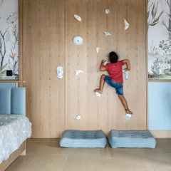 Designing for children is about sparking joy and curiosity. This bedroom features a custom rock-climbing wall that doubles as a playful art installation, encouraging adventure and activity. We believe kids' bedroom design should be imaginative, safe, and grow with them, and this space is a testament to that philosophy.