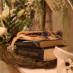A detail shot focusing on the props within our decor. A stack of classic books, a nest of dried twigs, and delicate thistles come together to build a rich, textured narrative.