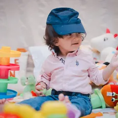 A toddler playing with a cap and his toys. We let kids be kids, capturing their natural curiosity and playful spirit during our indoor sessions.