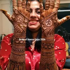A happy bride showing off her engagement mehendi. The back of her hands features personalized initials and infinity symbols, surrounded by intricate traditional bands.