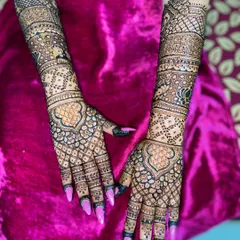A gorgeous full-hand mehandi design with a mix of grids, florals, and paisley patterns, creating a rich and dense look that extends up the arms.