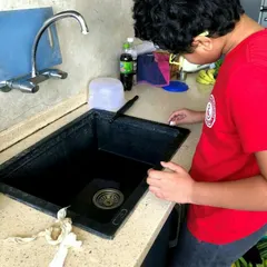 A young student gets a hands on lesson in plumbing by examining a kitchen sink. Our World Water Day module teaches kids about water conservation and responsible plumbing practices.