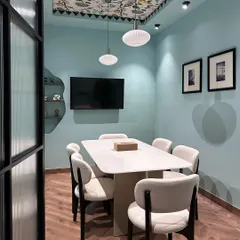 This is the main conference room in my studio. I used a serene blue on the walls and a custom-printed wallpaper on the ceiling tray to make the room feel unique. The space is equipped for presentations and collaborative work sessions.