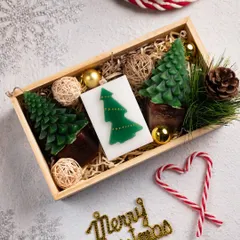 This wooden gift crate is packed with Christmas joy. It includes two detailed tree-shaped candles, a Christmas tree wax bar, and festive ornaments, all nestled in natural filler.