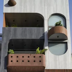 The façade of the Slender House is simple yet interesting, using corten steel texture paint, wooden battens, and grey tiles. The soft curves of the balconies and window openings are a recurring motif, extending from the exterior into the interior spaces.
