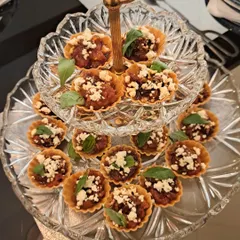 Here is a little taste of my gourmet side. These bite-sized tarts are filled with sweet caramelized onions and balsamic tomatoes, then topped with crumbled feta and fresh basil. They are an absolute treat for any party or gathering.