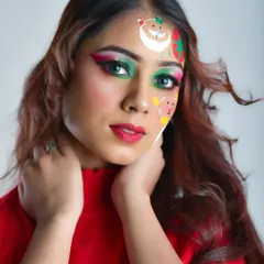 A fun and festive Christmas makeup look. This combines glamorous green and pink eyeshadow with playful, hand-painted face art of Santa, a snowman, and a reindeer for a unique holiday style.