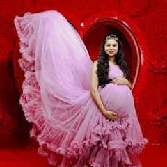 This dramatic maternity photo features a beautiful ruffled pink gown against a vibrant red heart backdrop in my studio. The long train creates a stunning visual effect.