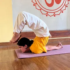 A student demonstrates an advanced variation of Salabhasana (Locust Pose), a powerful backbend that strengthens the entire back of the body and improves posture.