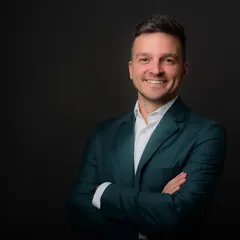 This standard corporate headshot with arms crossed is a popular choice for professionals wanting to project confidence and readiness. The simple dark backdrop keeps the focus entirely on the subject.