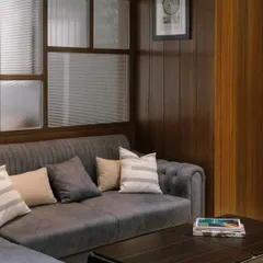A fluted glass partition provides visual privacy for this lounge area while allowing natural light to filter through. The rich wood frame and tufted sofa create a warm, textural contrast.