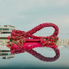 A life-sized infinity symbol made entirely of red and pink roses, serving as a mandap against the Persian Gulf. This design, reflected in the water, symbolized the couple's endless love.