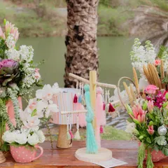 A close-up of the vibrant details from our 'Sunny Sway Soirée', including lush floral arrangements in polka-dot mugs and a colorful tassel tree.