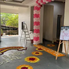 A beautiful flower rangoli design on the floor for a 'Welcome Home Little Princess' event, including a rainbow and footprint patterns.