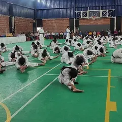 Students performing flexibility stretches during a belt exam. Physical conditioning is a critical component of our grading process.