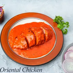 A plated view of our Oriental Chicken. You can see the stuffed chicken breast, sliced to show the filling, and generously coated in a smooth, orange gravy.
