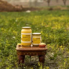 Barosi's ghee products photographed in a green field. This environmental shot powerfully communicates the brand's message of natural, farm-sourced ingredients.