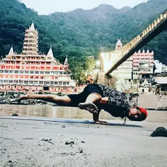 Performing Ek Paad Koundinyasana on the banks of the Ganga in Rishikesh. This arm balance requires core strength and focus, and practicing in such a spiritual place reminds us that yoga connects our physical self with a deeper energy.