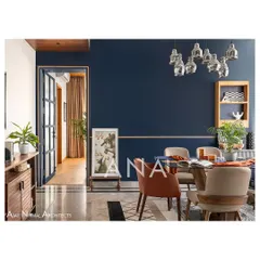 The dining area in Apartment 704 features a vibrant blue wall, creating a playful contrast to the minimal living space. Antique wooden beams on the ceiling and mismatched leatherette chairs add character and warmth, perfect for hosting.