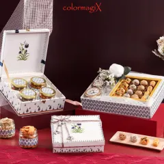 An elegant white and blue floral themed Diwali hamper set. This collection includes a large box for sweets and smaller matching jars for dry fruits, perfect for sophisticated festive gifting.