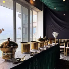 Our full-service catering includes creating a sophisticated ambiance. Here, you can see our elegant brass chafing dishes and coordinated green and gold decor, which we set up to ensure your event looks as incredible as the food tastes.