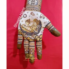 A clear view of the palm from a custom godh bharai mehendi design. It features a depiction of a baby sleeping on the moon, surrounded by baby-themed elements like a rattle, safety pin, and tiny shoes.